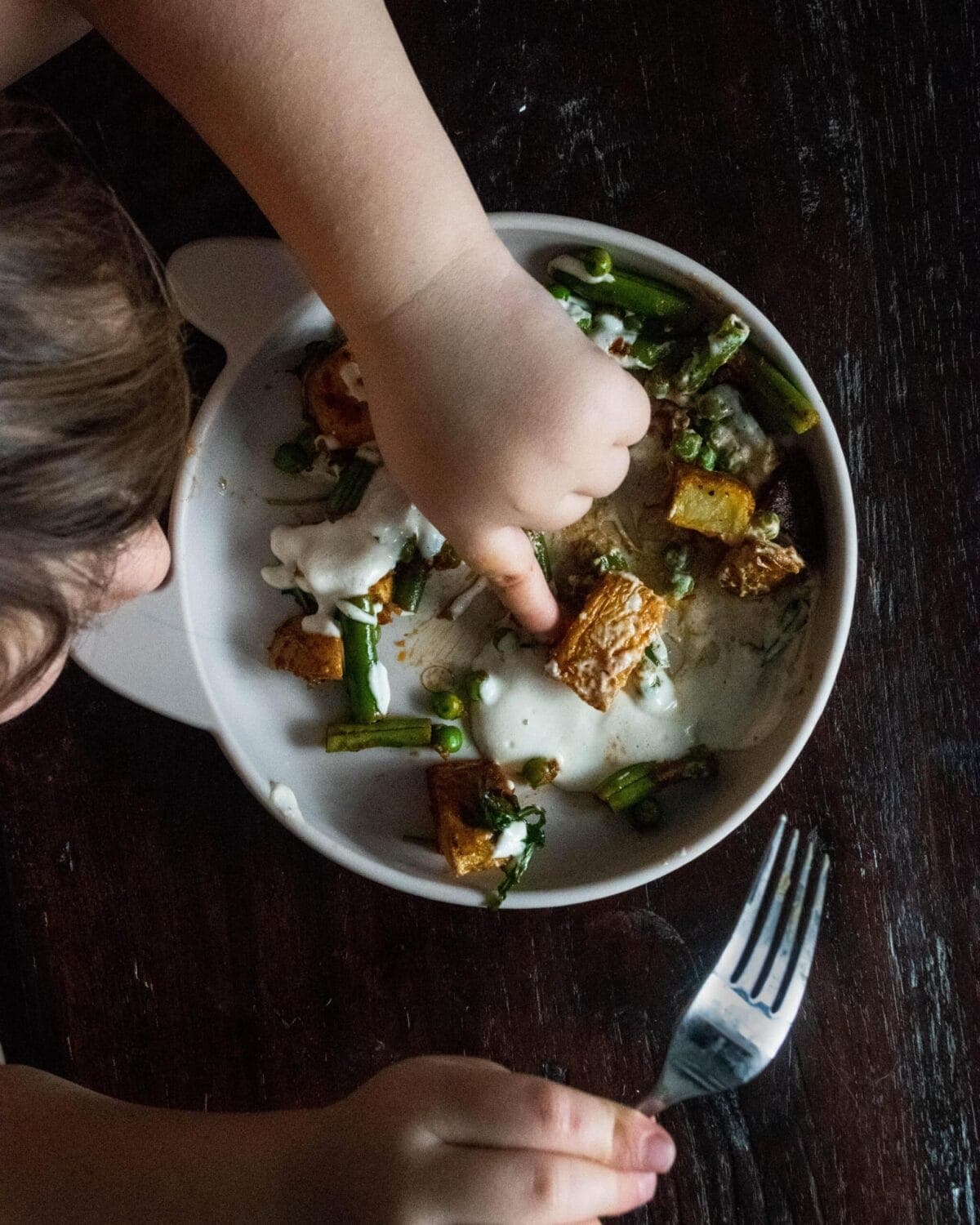 A toddlers plate filled with a serving of Green Beans and Potatoes with Harissa Pesto