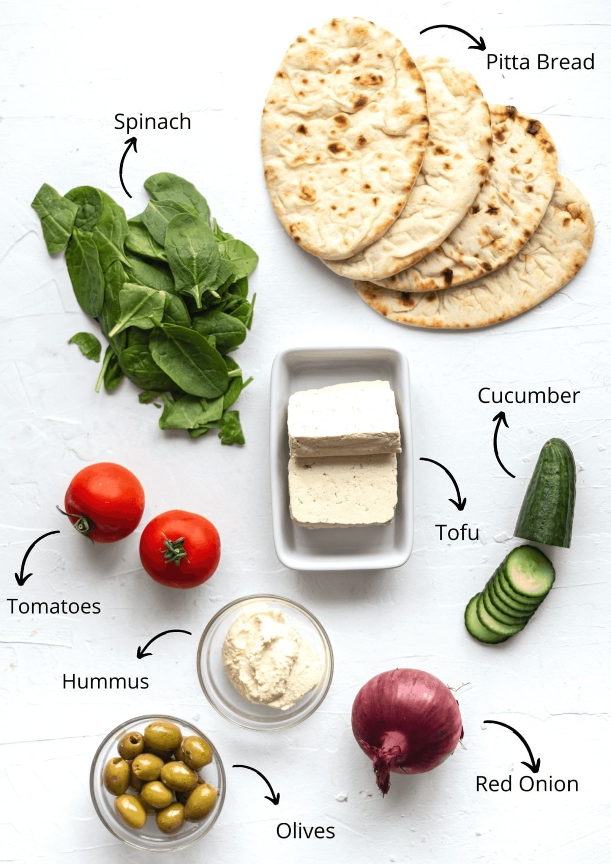 Overhead view of pittas, hummus, Tofu and the salad ingredients.