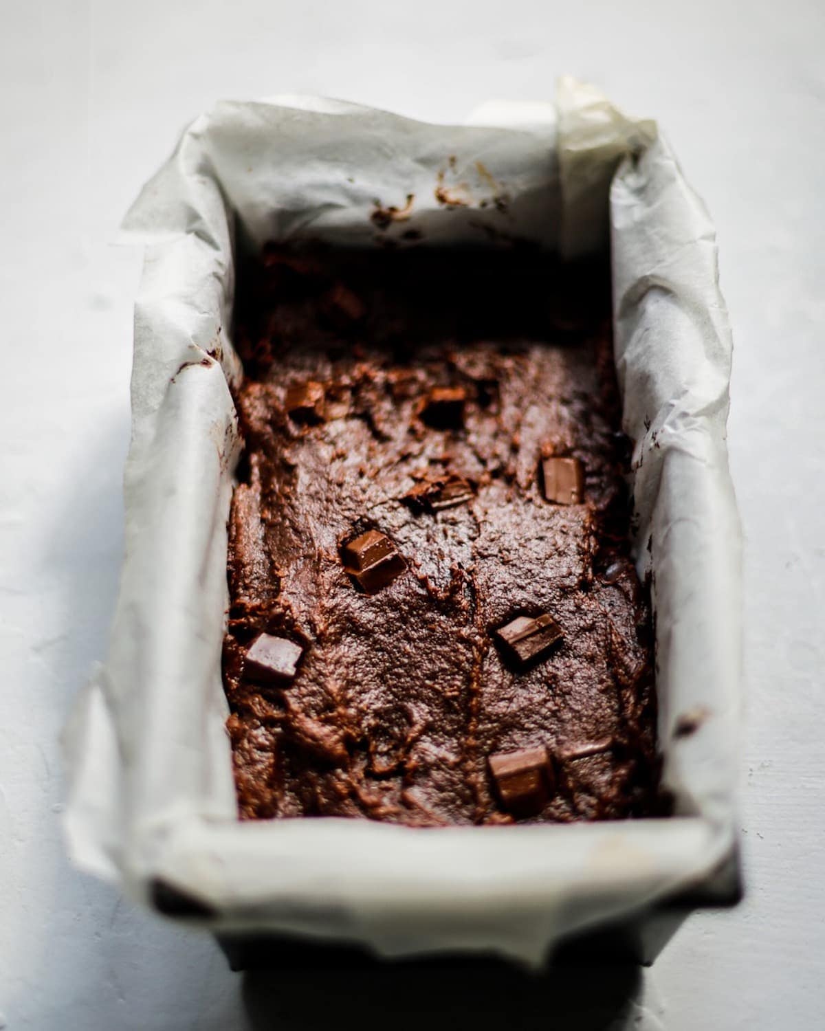 The brownie mixture in a baking tin, lined with baking paper.