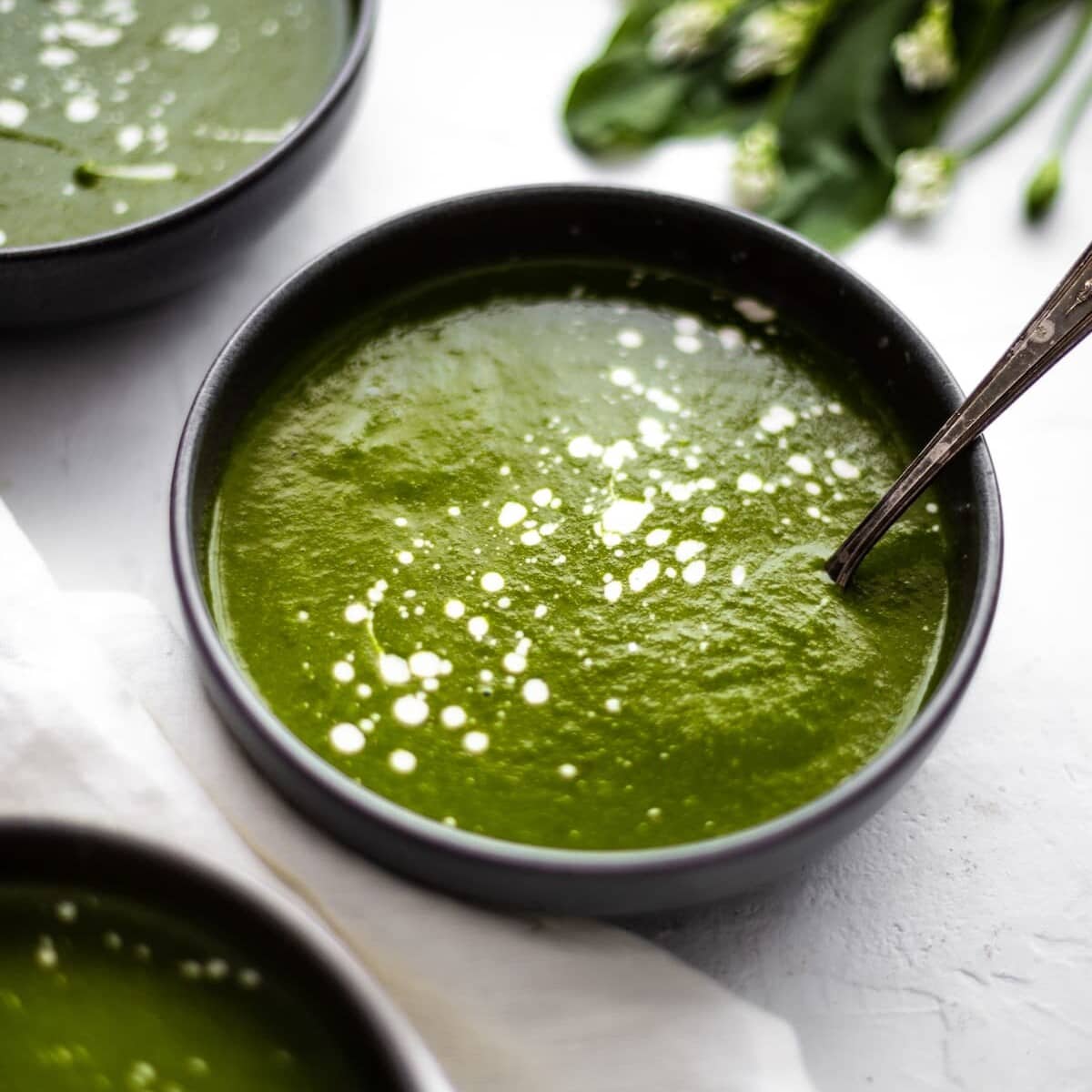 A bowl of wild garlic soup with a spoon in it.