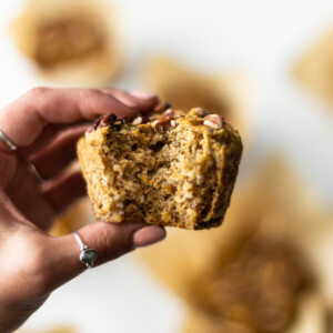Yasmin holding a muffin up in front of the camera, with a bite taken out of it.