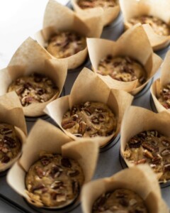 A tray full of unbaked banana and pecan muffins.