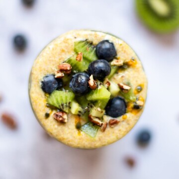 An overhead view of a jar of flaxseed pudding, topped with fresh blueberries, chopped kiwi and chopped pecans,