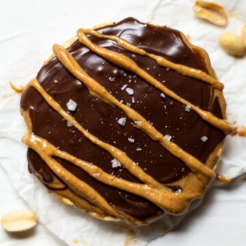 A rice cake, topped with peanut butter, melted chocolate and flaky sea salt.