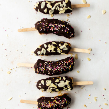 Six chocolate coated banana lollies topped with sprinkles and flaked almonds.